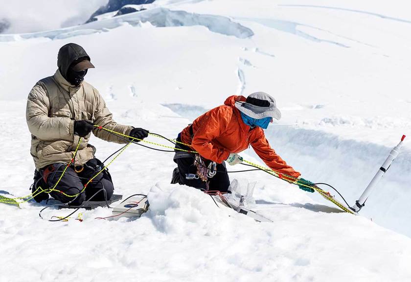 Two people setting up equipment in the ice