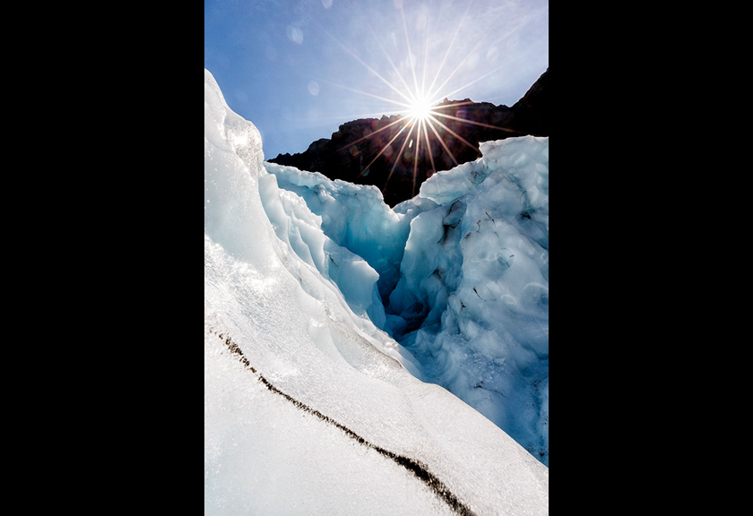 Sunbeam shining through a gap in icy glacier formations