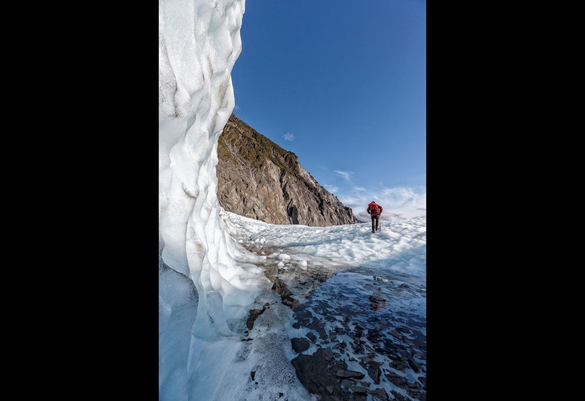 Person navigating rugged, icy terrain on glacier