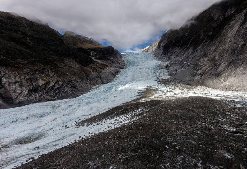 Wide view of glacier pushing through mountain ranges