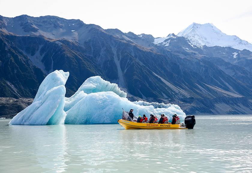 Group of people in small boat passing an ice formation