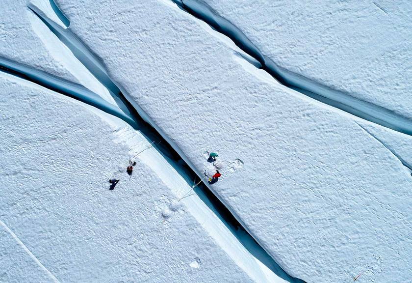 Aerial view of people navigating over an ice crevasse