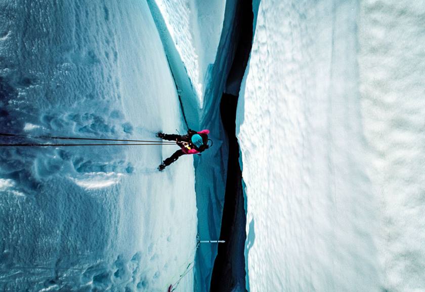 Aerial view of person descending down an ice crevasse on a