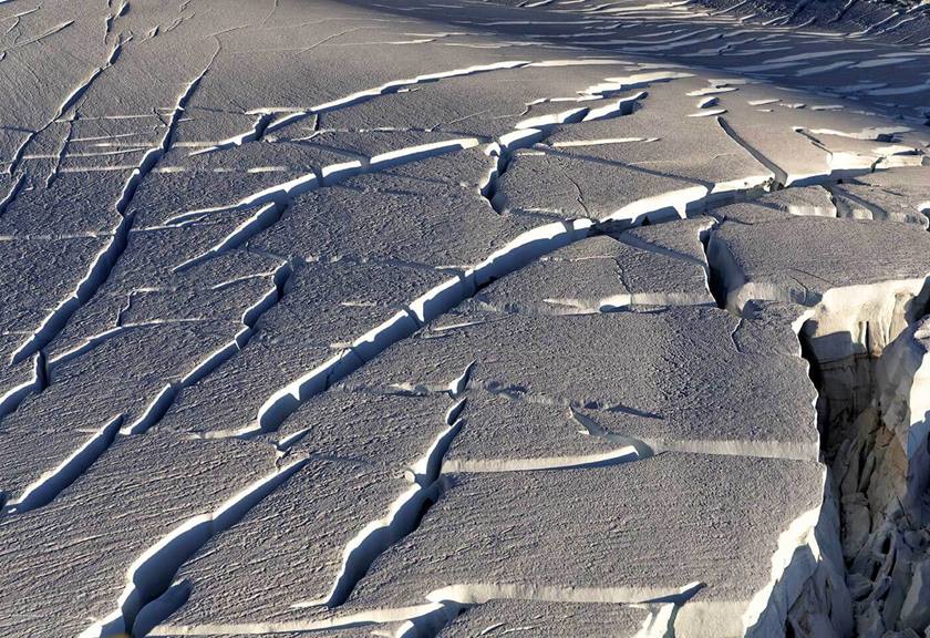 Aerial view of wind affected snow and ice with dramatic shadows cast by sun and cloud