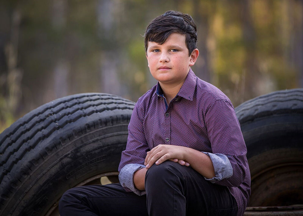 portrait image of boy sitting on tires