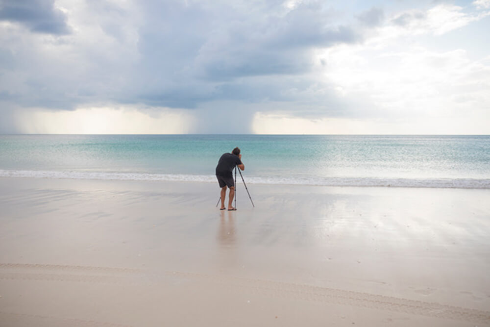 Photographer using a tripod to take a seascape image