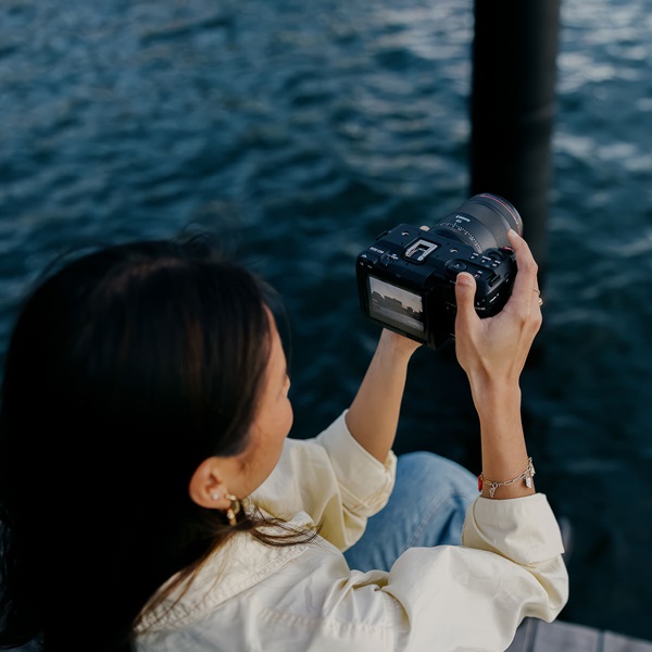 Image of a woman using her Canon camera to photograph in front of the ocean