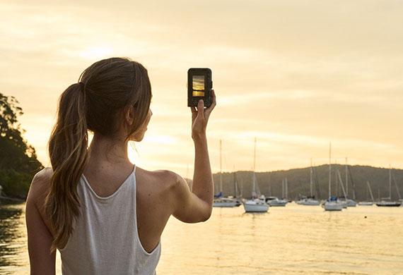 Image of a woman using a Canon camera to capture boats in the lake