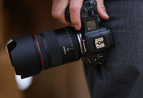 Image of a Canon EOS camera with a telephoto lens on hand