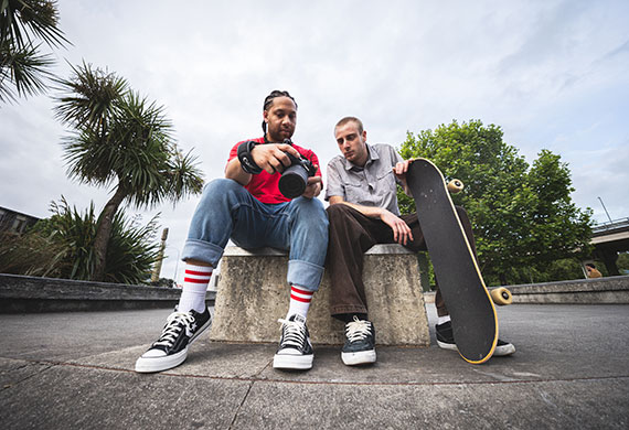 Image of skaters sitting down holding their skateboard and camera