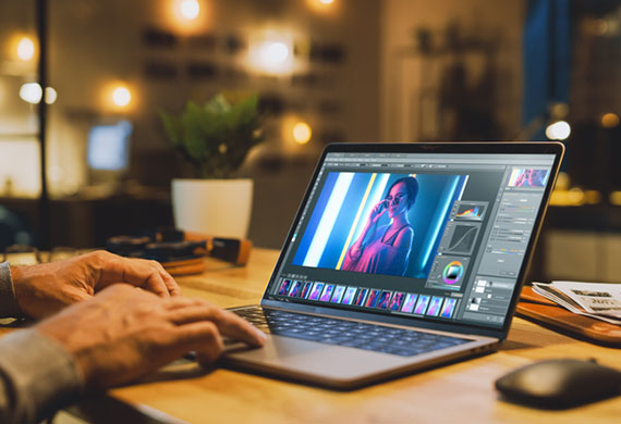 Image of a photography editor using an editing software on their laptop