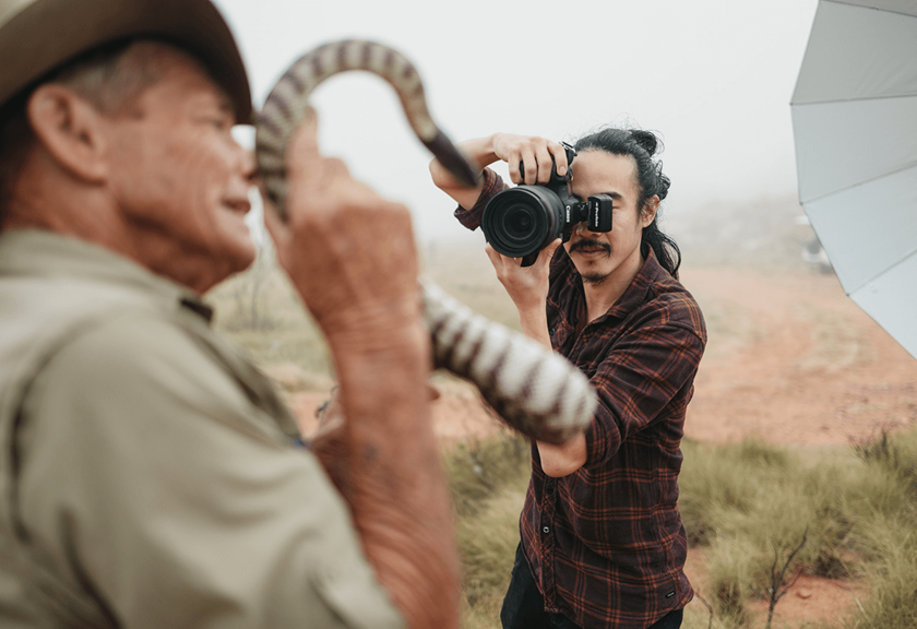 Jarrad Seng taking a photo of Brian Bush holding a snake