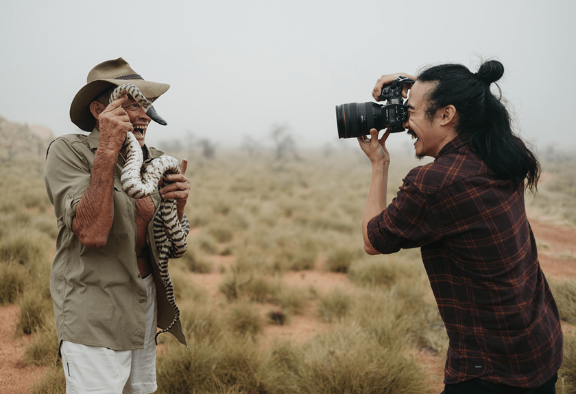 Jarrad Seng taking a photo of Brian Bush holding a snake