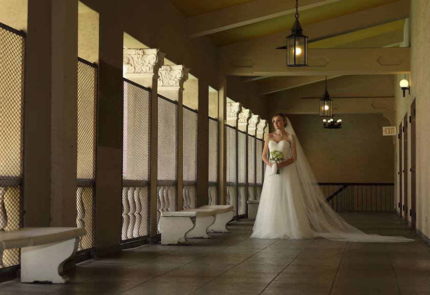 wide shot image of bride with bouquet standing in hallway