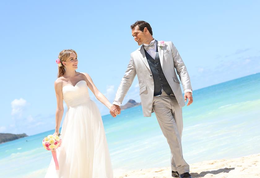 portrait  image of bride and groom holding hands on beach