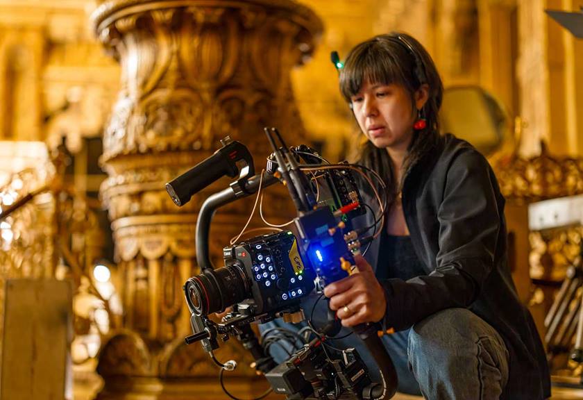 A woman crouching and starting into a camera rig with concentration, preparing for a video shoot