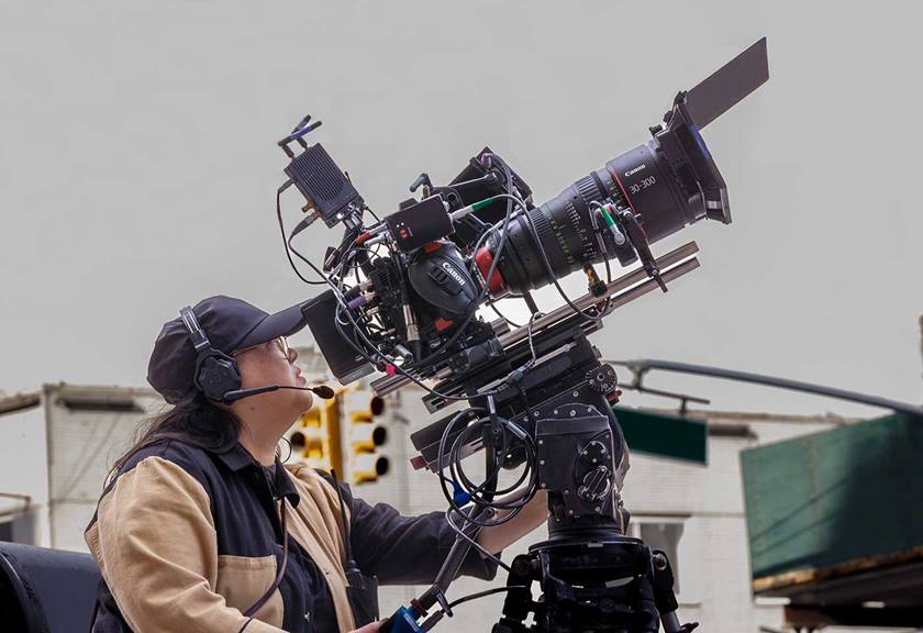 Women with headset operating big camera and lens on a tripod, ready to capture a moment