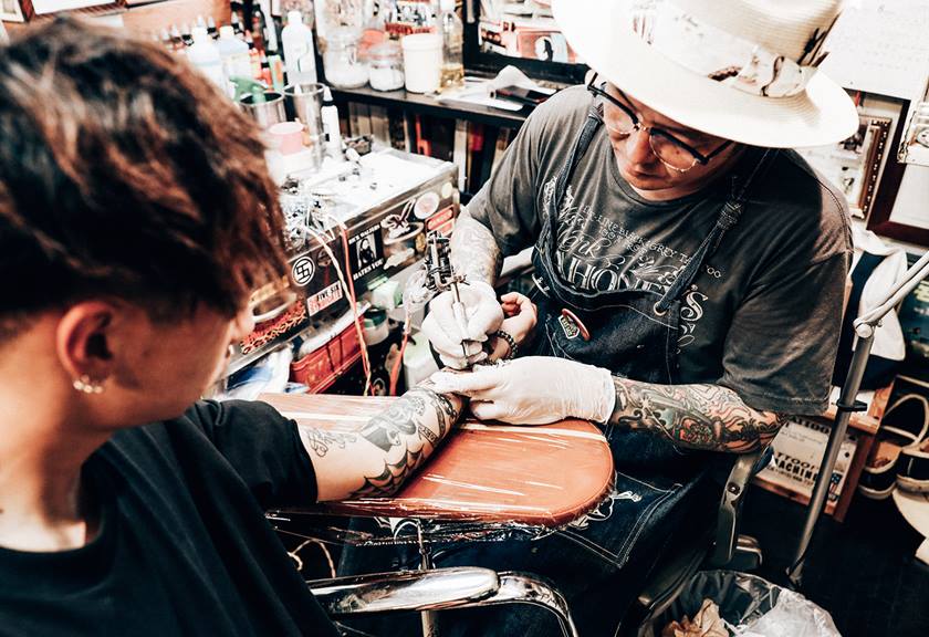 Image of a tattoo artist with a client. Shot with the EOS R