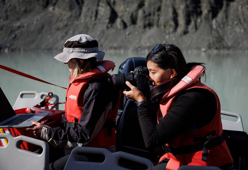 Two people in boat, one person photographing the view