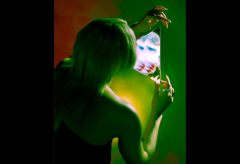 Fashion photography image of a woman holding a triangle mirror in green lighting by MACAMI