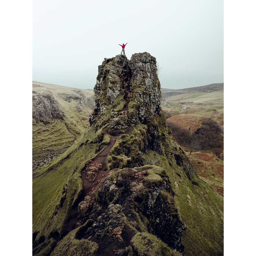 Girl in red on top of rock formation in Scotland