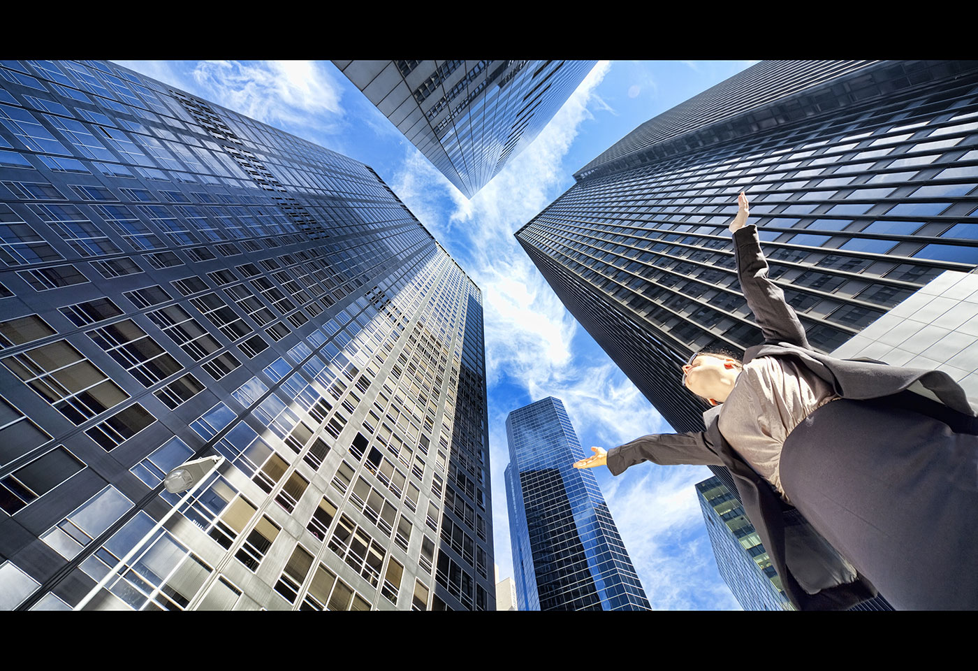 Bottom view image of skyscrapers and a woman raising her hands