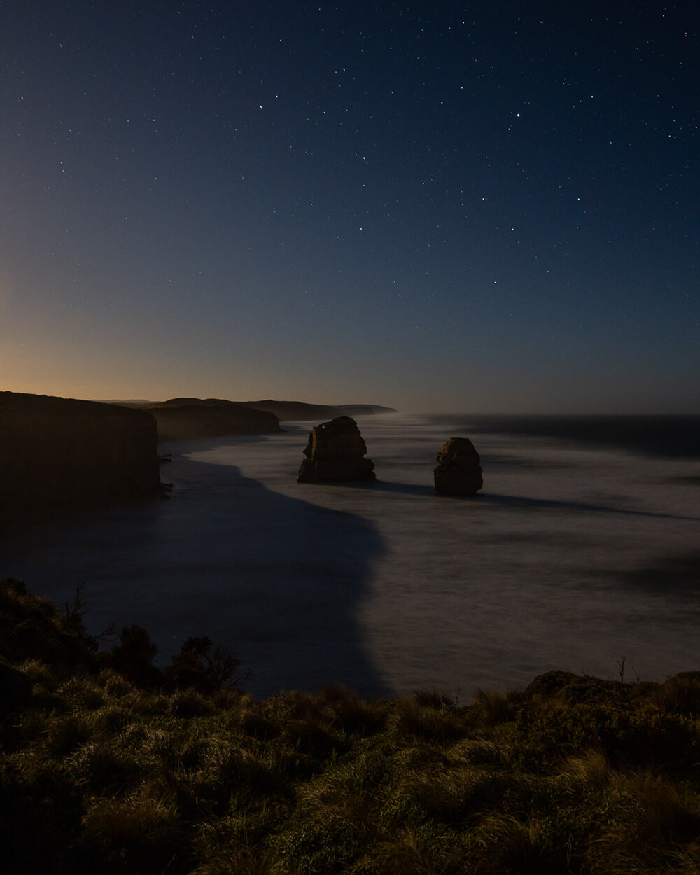 Low light image of rocks in a lake by Julian Lallo