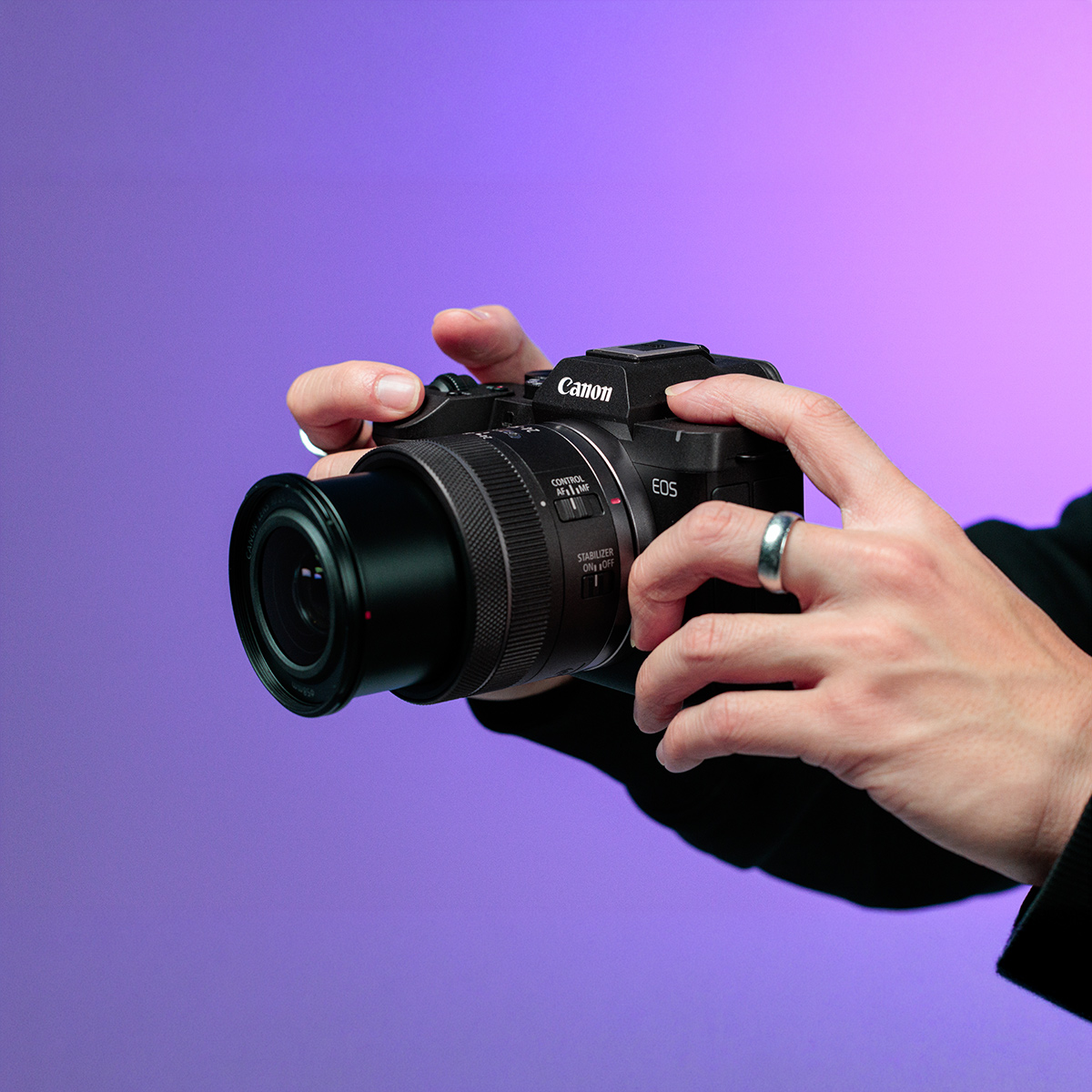 Person holding a Canon EOS R8 Mark II camera ready to take a photograph in a studio setting