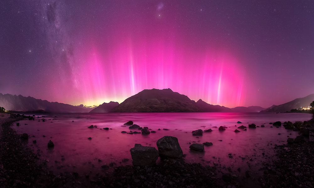 Image of pink aurora and star trail in the mountains by Larryn Rae