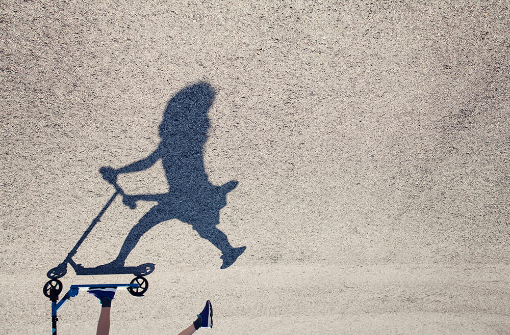 Shadow on pavement of child on scooter