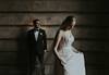 Image of bride looking at her dress with groom on the background by James Simmons