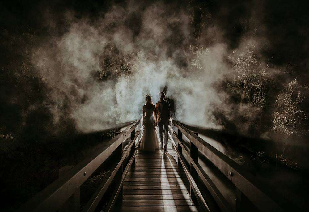 Bride and groom on a bridge in a foggy area taken by James Simmons