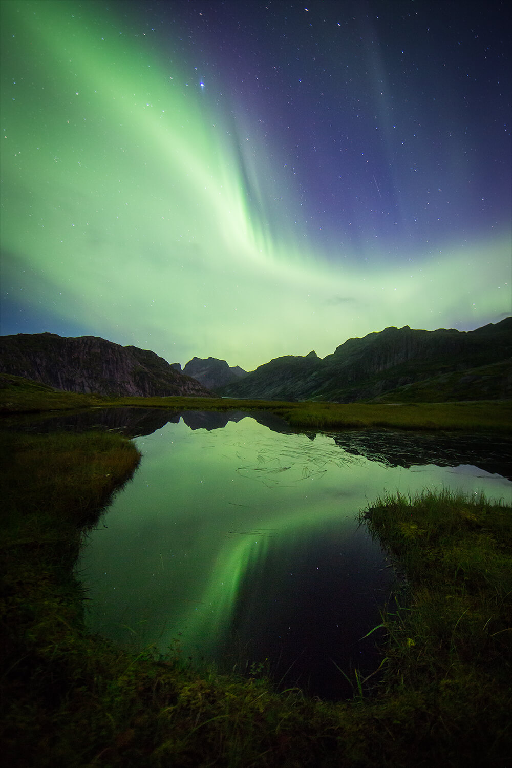 Image of the Northern Lights and its reflection on a lake. Photo by Neal Bloem