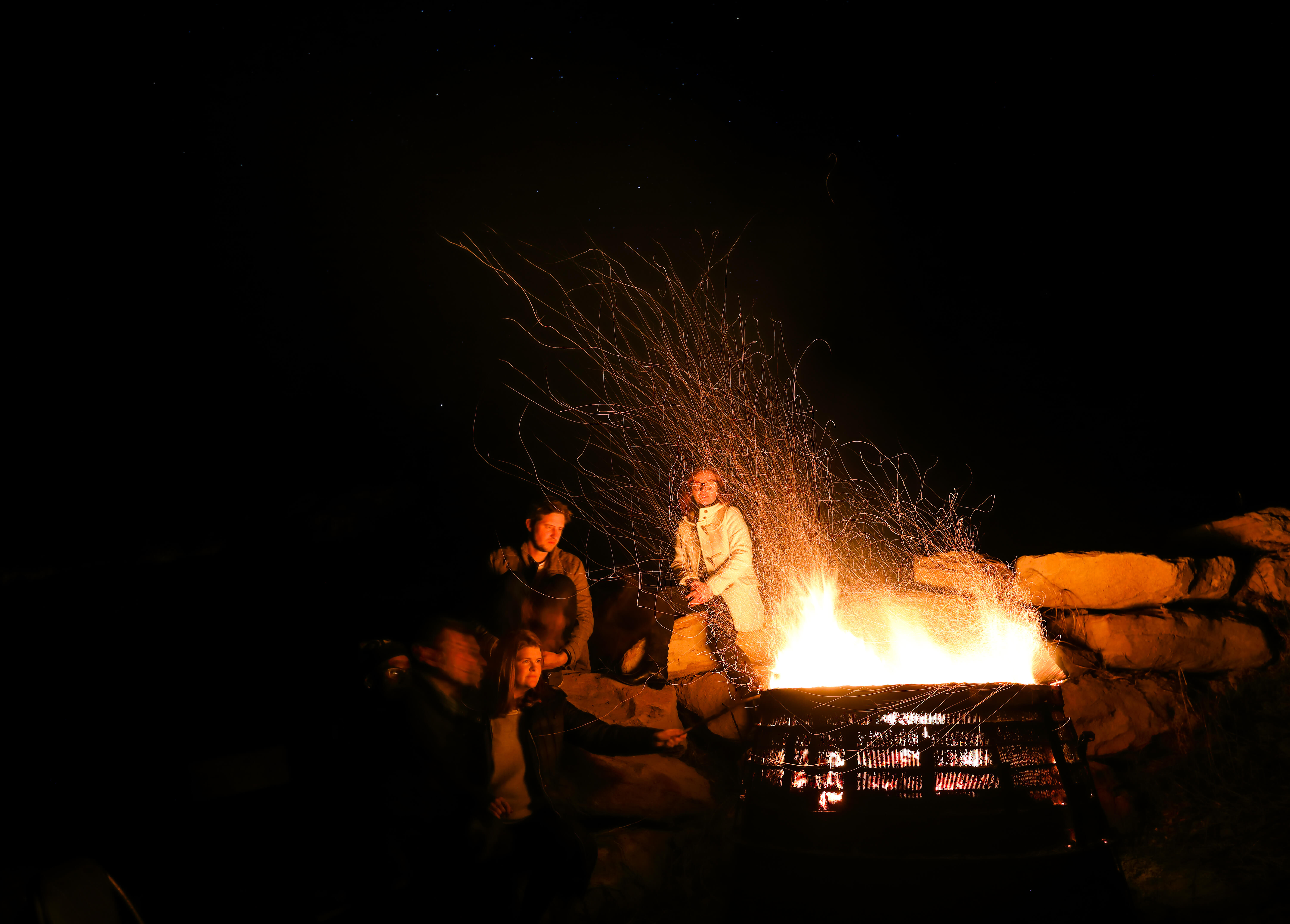 Image of friends around a campfire with sparks flying by Dr Chris Brown