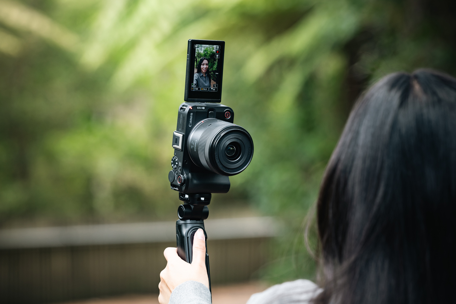 Image of a woman using her Canon EOS R50 V in a forest