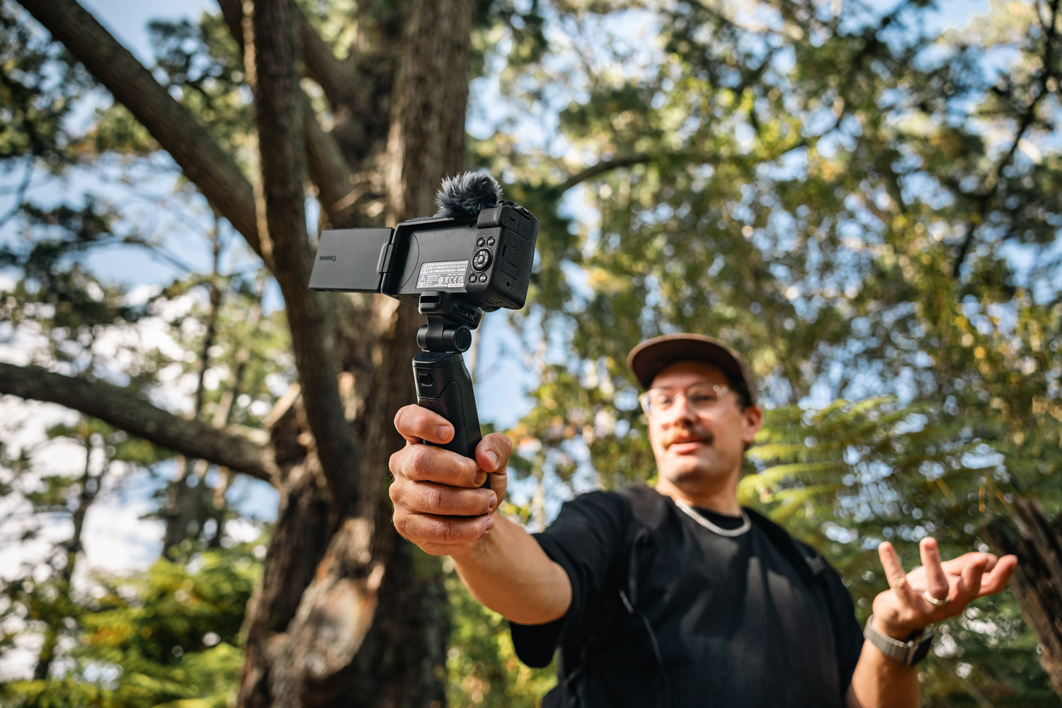 Image of a man using his Canon EOS R50 V in a forest