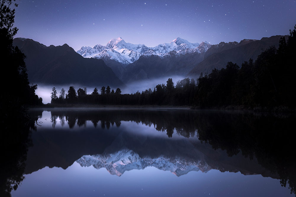 Image of a forest reflecting on water. Photo by Rach Stewart