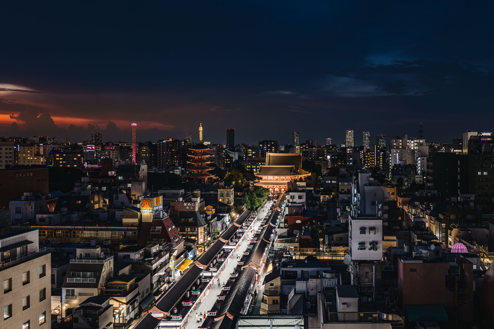 Tokyo street leading towards Asakusa temple beneath a red sunset sky