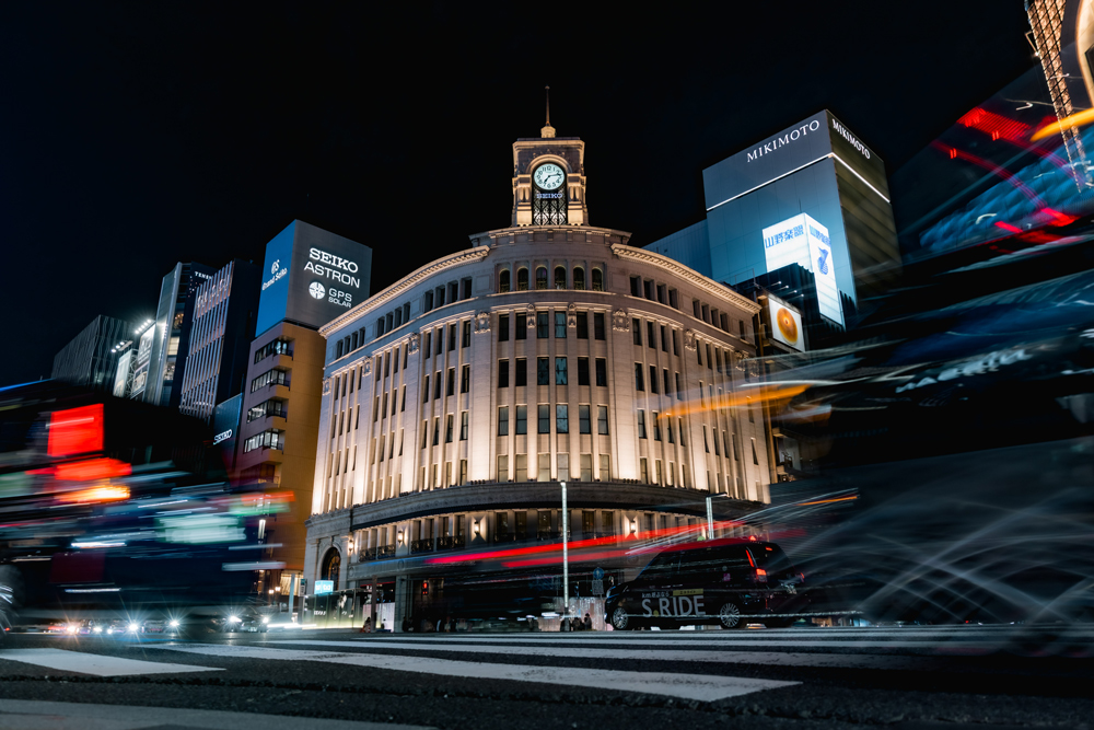 Passing traffic in the foreground with the illuminated Ginza clock tower at night