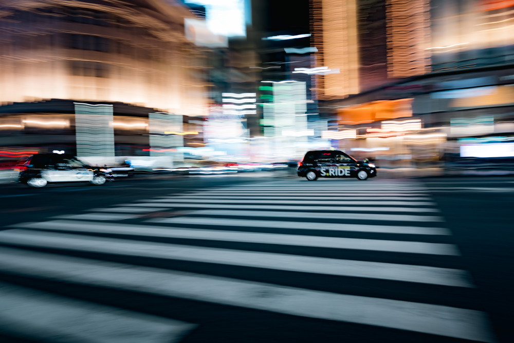 Moving vehicle surrounded by streaks of light on a busy Ginza street at night
