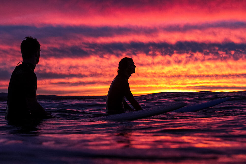 Portrait image of surfers at sunset