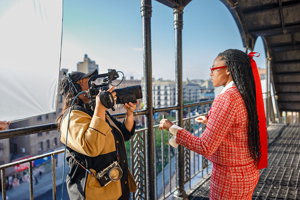 Woman holding large camera with long lens during a shoot on a balcony