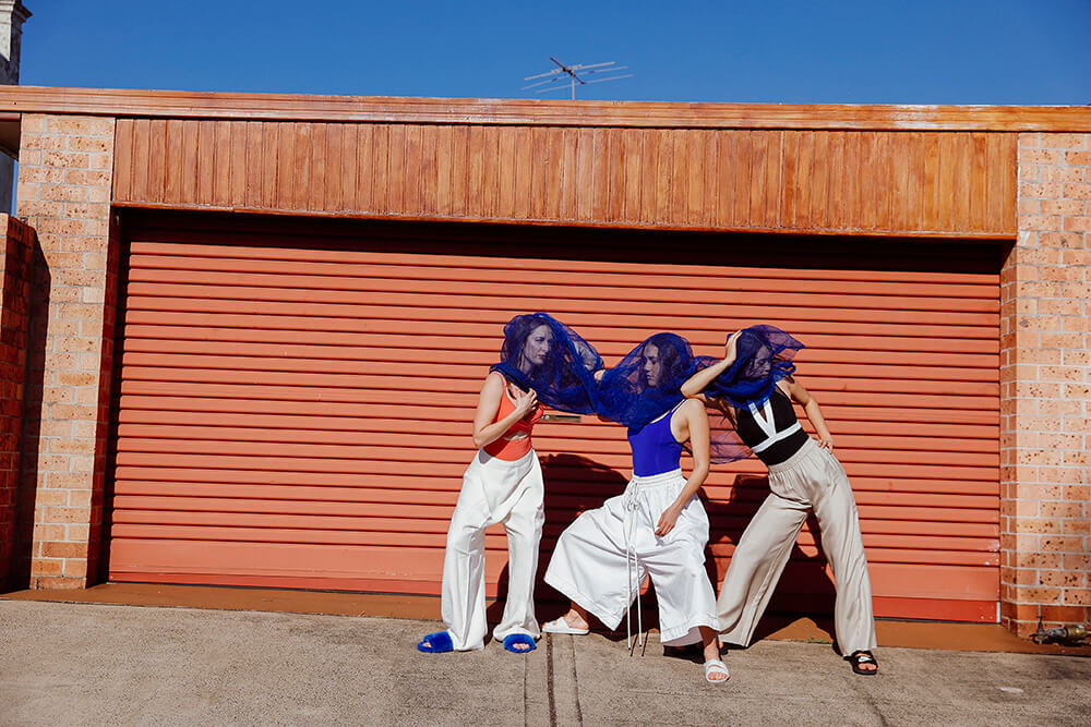 Portrait image of three women under blue fabric