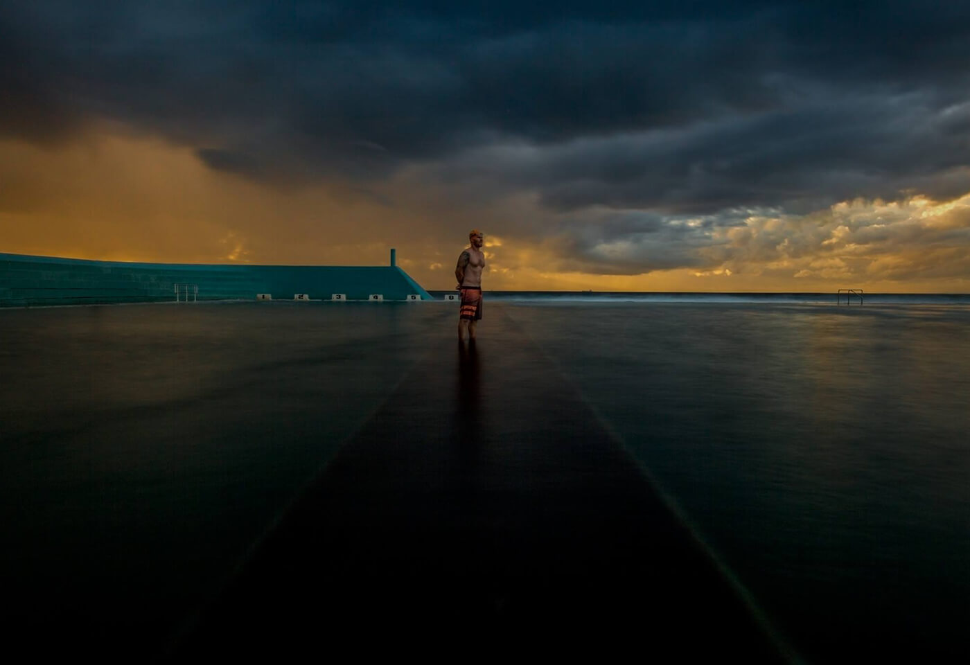 Image of man standing in beach pool at dawn