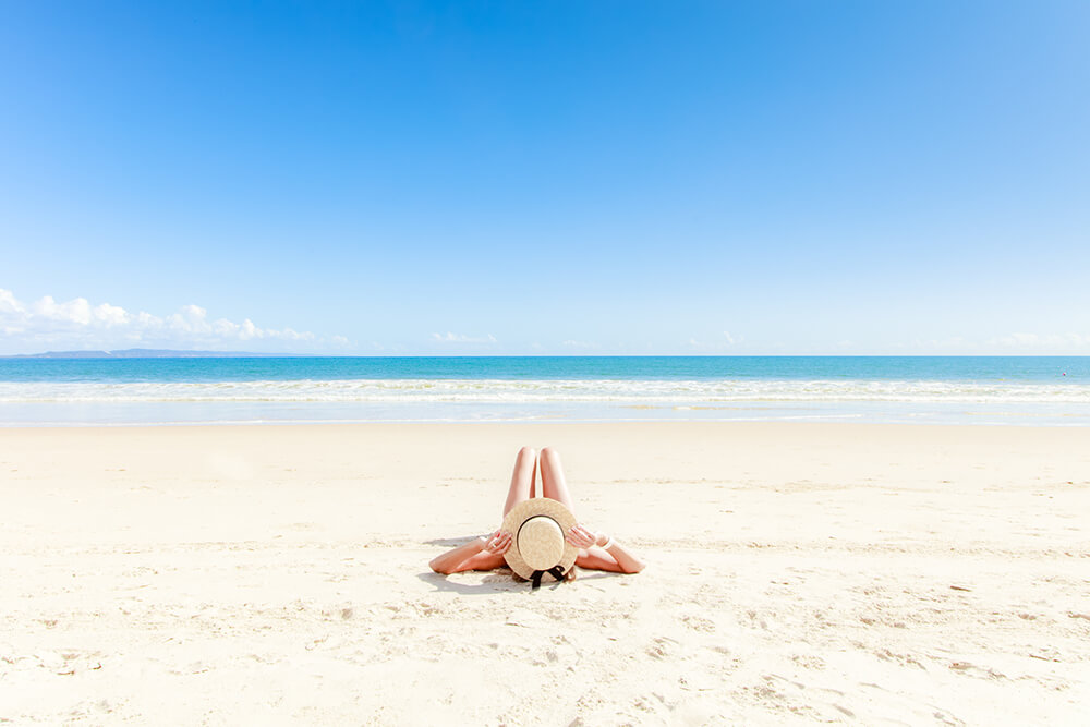 Lady with hat sunbathing by the beach