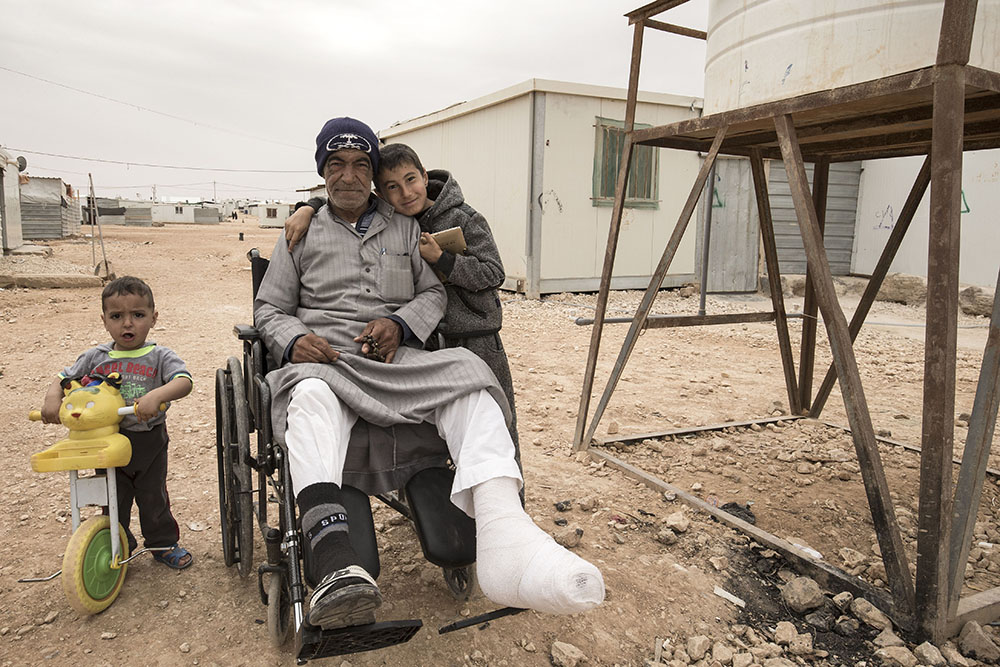 Image of refugee kids around wheelchair bound man