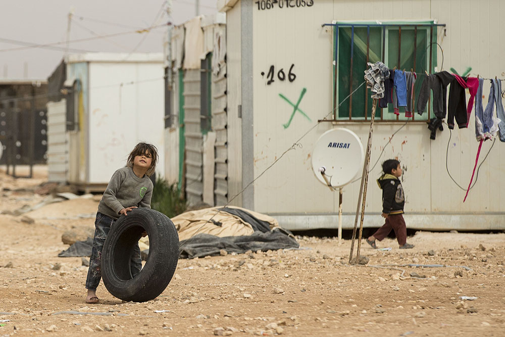 image of a refugee kid playing with tyre