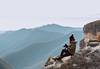 Photograoher with EOS 6D Mark II sitting on mountain top