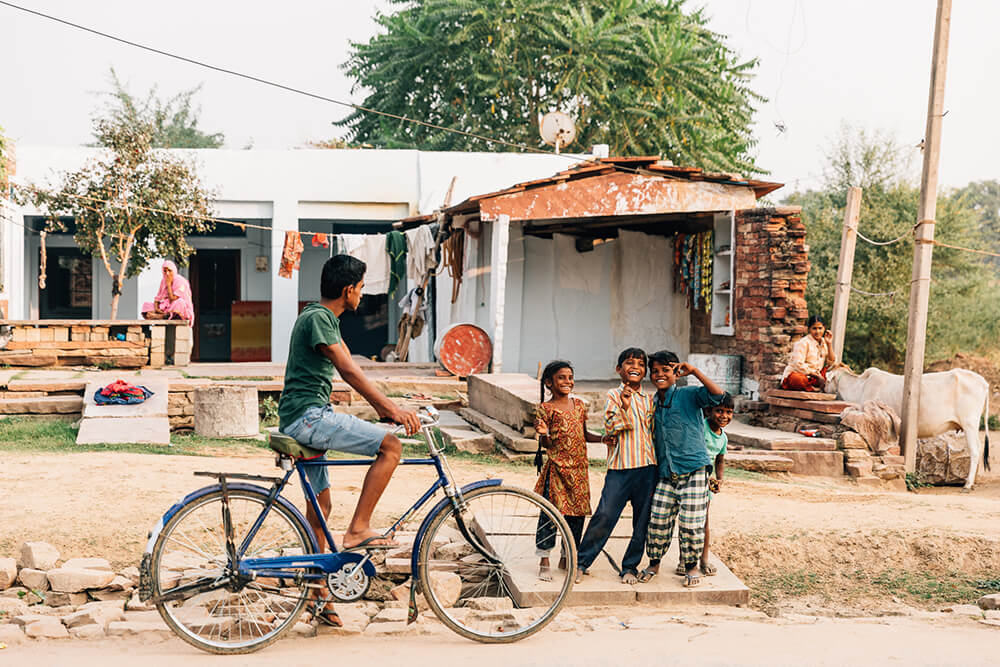 Photo of a cyclist and kids in a street in India. Image by Melissa Findley