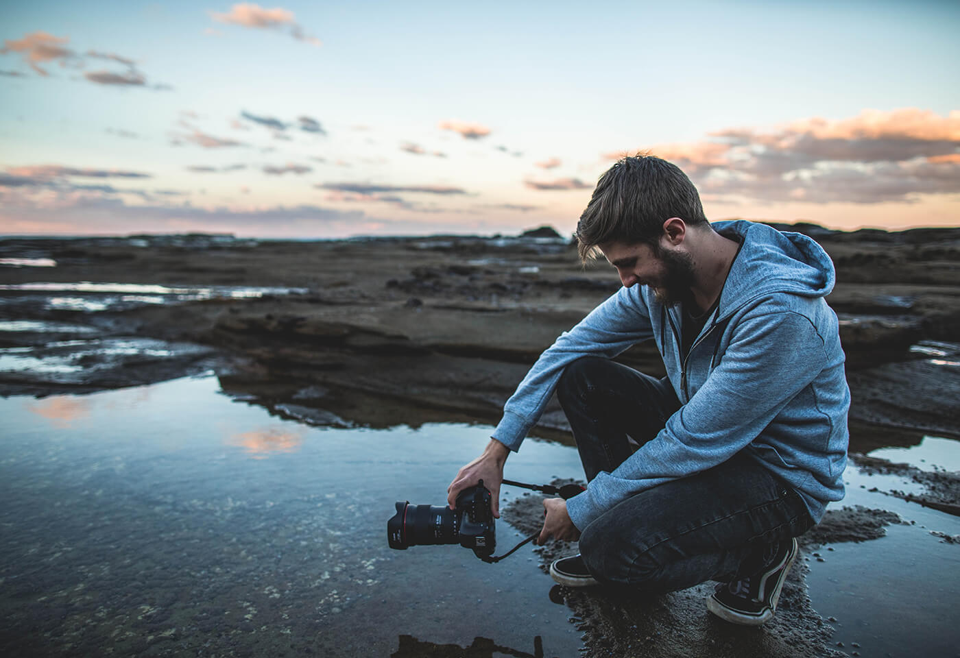 Photographer holding Canon 6D Mark II by rock pool